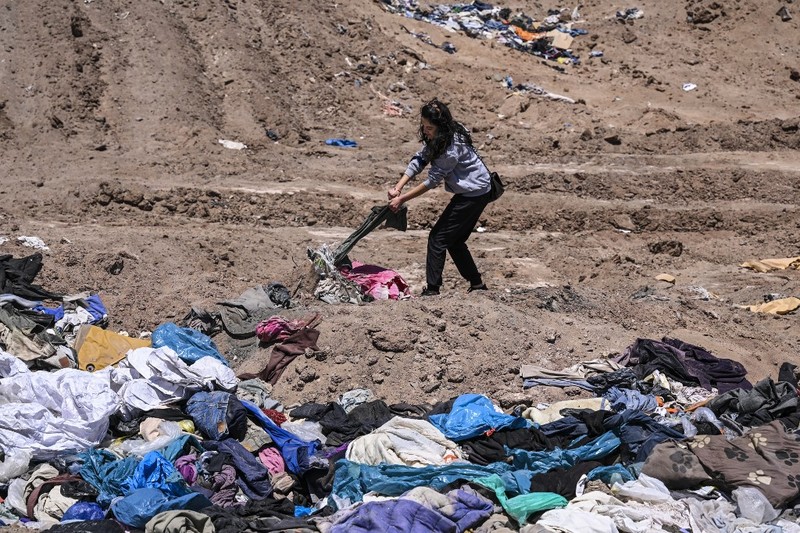 Pengacara Paulina Silva menunjukkan pakaian yang dibuang di padang pasir, di sektor La Pampa di Alto Hospicio, Gurun Atacama, Chili, Sabtu (12/11/2022). Gurun Atacama yang juga merupakan lokasi penelitian ilmiah untuk hidup di Mars merupakan daerah terkering di Bumi terancam oleh tumpukan sampah yang dibuang ke sana dari seluruh dunia. Setiap tahunnya ada lebih dari 46.000 ton sampah dikirim ke gurun pasir yang ada di antara Andes dan rangkaian pengunungan Chili. (Photo by MARTIN BERNETTI / AFP)