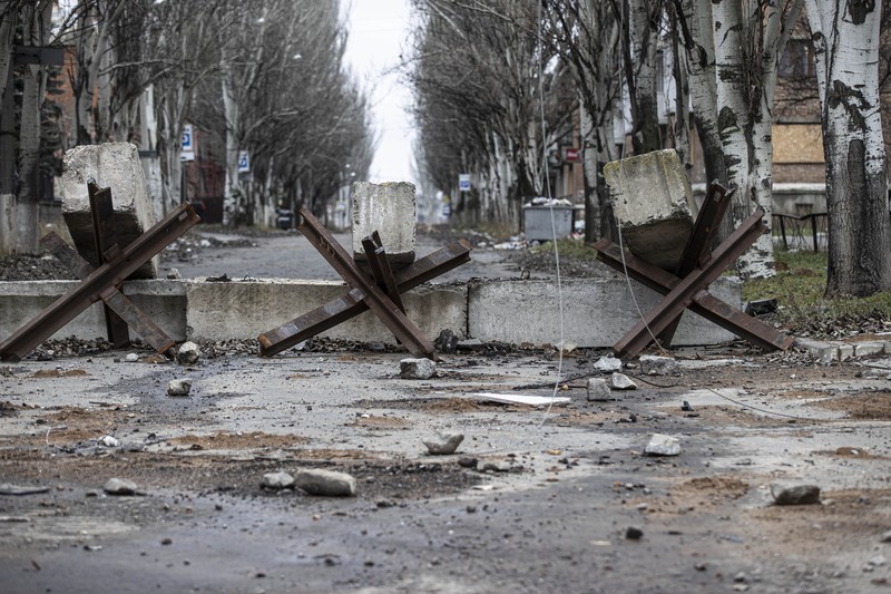 Pemandangan barikade jalan anti-tank di kota Bakhmut, Ukraina, titik nyala perang Rusia yang sekarang memasuki bulan kesembilan pada 25 November 2022. Kota itu telah ditinggalkan oleh penduduknya karena serangan Rusia menghancurkan infrastruktur dan mengganggu layanan penting seperti gas , listrik dan air. Mereka yang tertinggal menghindari keluar rumah dan tetap tinggal di tempat perlindungan bom. Setelah jembatan utama di pusat kota hancur dalam pengeboman, penduduk yang pergi ke desa tetangga untuk membeli air, makanan, dan kebutuhan sehari-hari lainnya terdampar. Beberapa orang terpaksa menempuh perjalanan jauh dengan sepeda untuk mencari makanan dan air, sementara yang lain berjalan di atas saluran pipa yang berbahaya di tengah sungai. Sebelum perang, kota ini adalah rumah bagi 80.000 orang. Kini, 90 persen warga telah mengungsi ke tempat yang lebih aman. (Metin Aktas/Anadolu Agency via Getty Images)