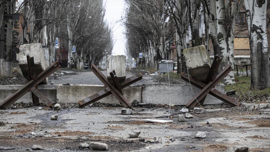 Pemandangan barikade jalan anti-tank di kota Bakhmut, Ukraina, titik nyala perang Rusia yang sekarang memasuki bulan kesembilan pada 25 November 2022. Kota itu telah ditinggalkan oleh penduduknya karena serangan Rusia menghancurkan infrastruktur dan mengganggu layanan penting seperti gas , listrik dan air. Mereka yang tertinggal menghindari keluar rumah dan tetap tinggal di tempat perlindungan bom. Setelah jembatan utama di pusat kota hancur dalam pengeboman, penduduk yang pergi ke desa tetangga untuk membeli air, makanan, dan kebutuhan sehari-hari lainnya terdampar. Beberapa orang terpaksa menempuh perjalanan jauh dengan sepeda untuk mencari makanan dan air, sementara yang lain berjalan di atas saluran pipa yang berbahaya di tengah sungai. Sebelum perang, kota ini adalah rumah bagi 80.000 orang. Kini, 90 persen warga telah mengungsi ke tempat yang lebih aman. (Metin Aktas/Anadolu Agency via Getty Images)