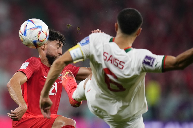 Pemain Kanada Jonathan Osorio (kiri) berebut bola dengan pemain Maroko, Romain Saiss selama pertandingan sepak bola grup F Piala Dunia antara Kanada dan Maroko di Stadion Al Thumama di Doha, Qatar, Kamis (1/12/2022). Maroko mengalahkan Kanada 2-1 dalam laga terakhir Grup F Piala Dunia 2022. Hasil ini mengantarkan Singa Atlas melaju ke 16 besar.  (AP Photo/Manu Fernandez)