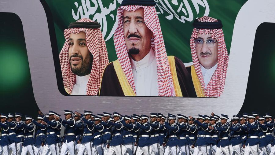 Perwira angkatan udara Saudi yang baru lulus berbaris di depan spanduk bergambar Raja Salman bin Abdulaziz (tengah), Putra Mahkota Mohammed bin Nayef (kanan), dan wakil Putra Mahkota Mohammed bin Salman selama upacara yang menandai peringatan 50 tahun pembentukan Akademi Udara Raja Faisal di pangkalan udara Raja Salman di Riyadh pada 25 Januari 2017. (FAYEZ NURELDINE/AFP via Getty Images)