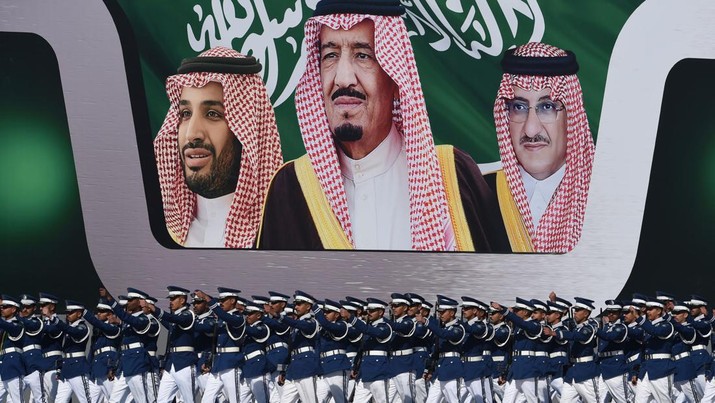 Raja Salman bin Abdulaziz (tengah), Putra Mahkota Mohammed bin Nayef (kanan), dan wakil Putra Mahkota Mohammed bin Salman Perwira angkatan udara Saudi yang baru lulus berbaris di depan spanduk bergambar Raja Salman bin Abdulaziz (tengah), Putra Mahkota Mohammed bin Nayef (kanan), dan wakil Putra Mahkota Mohammed bin Salman selama upacara yang menandai peringatan 50 tahun pembentukan Akademi Udara Raja Faisal di pangkalan udara Raja Salman di Riyadh pada 25 Januari 2017. (FAYEZ NURELDINE/AFP via Getty Images)