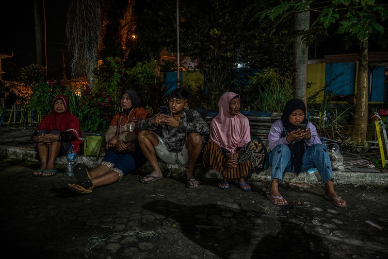 1245357442 People take temporary shelter in a room at a community hall in Candipuro village following Mount Semeru's volcanic eruption in Lumajang, East Java on December 4, 2022. (Photo by JUNI KRISWANTO / AFP) (Photo by JUNI KRISWANTO/AFP via Getty Images)