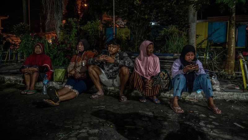 People take temporary shelter in a room at a community hall in Candipuro village following Mount Semeru's volcanic eruption in Lumajang, East Java on December 4, 2022. (Photo by JUNI KRISWANTO / AFP) (Photo by JUNI KRISWANTO/AFP via Getty Images)