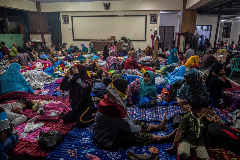 People take temporary shelter in a room at a community hall in Candipuro village following Mount Semeru's volcanic eruption in Lumajang, East Java on December 4, 2022. (Photo by JUNI KRISWANTO / AFP) (Photo by JUNI KRISWANTO/AFP via Getty Images)