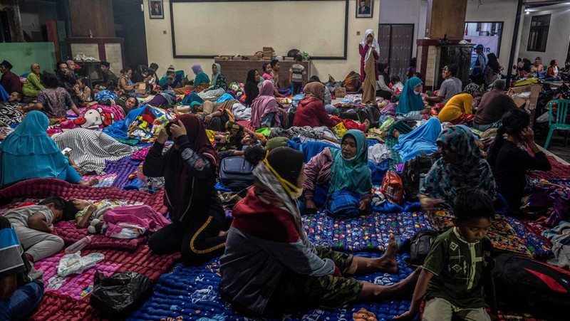 People take temporary shelter in a room at a community hall in Candipuro village following Mount Semeru's volcanic eruption in Lumajang, East Java on December 4, 2022. (Photo by JUNI KRISWANTO / AFP) (Photo by JUNI KRISWANTO/AFP via Getty Images)