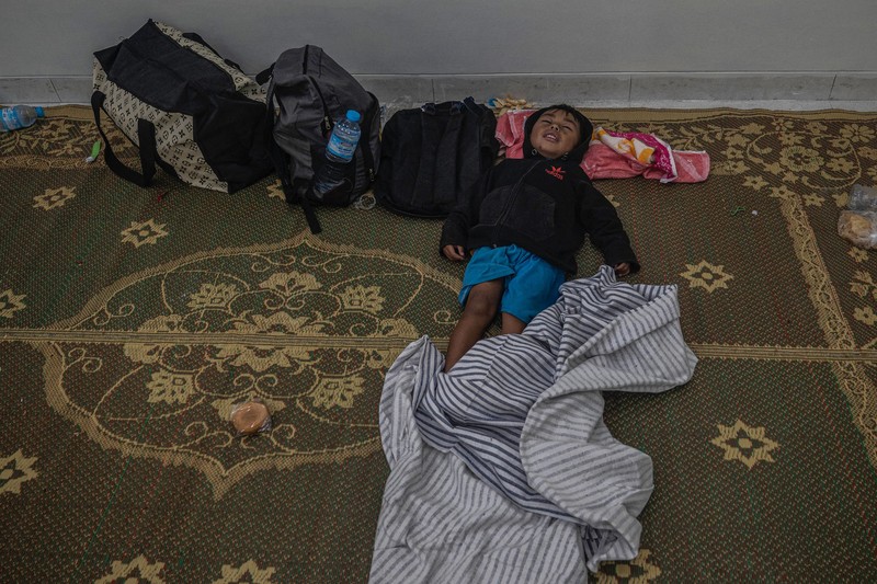 1245357442 People take temporary shelter in a room at a community hall in Candipuro village following Mount Semeru's volcanic eruption in Lumajang, East Java on December 4, 2022. (Photo by JUNI KRISWANTO / AFP) (Photo by JUNI KRISWANTO/AFP via Getty Images)