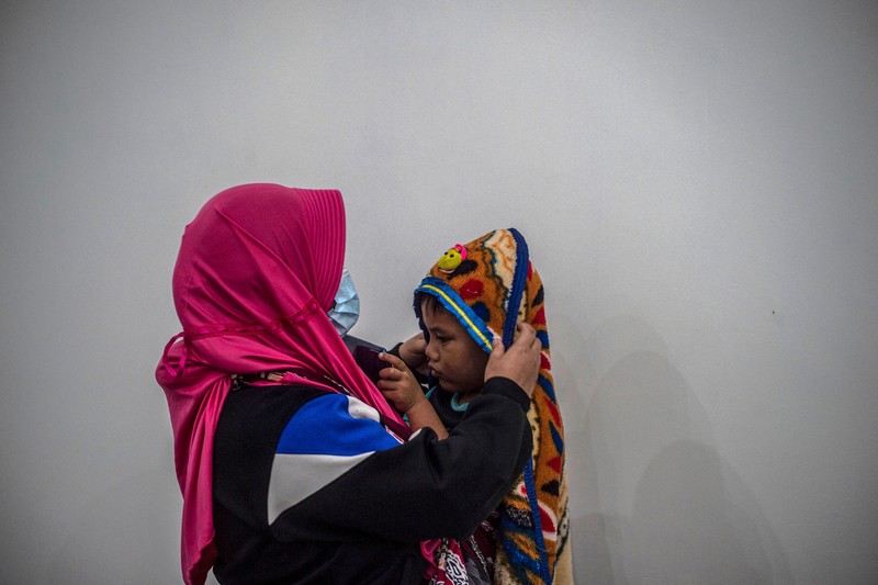 1245357442 People take temporary shelter in a room at a community hall in Candipuro village following Mount Semeru's volcanic eruption in Lumajang, East Java on December 4, 2022. (Photo by JUNI KRISWANTO / AFP) (Photo by JUNI KRISWANTO/AFP via Getty Images)