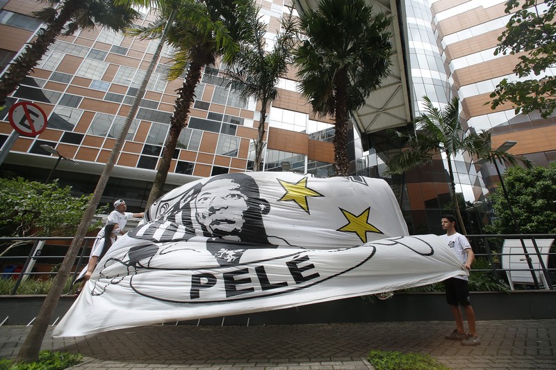 Fans mengadakan acara untuk mendukung legenda sepak bola Pele yang tetap dirawat di rumah sakit karena infeksi pernapasan di tengah perawatan kanker usus besar yang sedang berlangsung di Rumah Sakit Israel Albert Einstein pada 4 Desember 2022 di Sao Paulo, Brasil. (Mauro Horita/Getty Images)