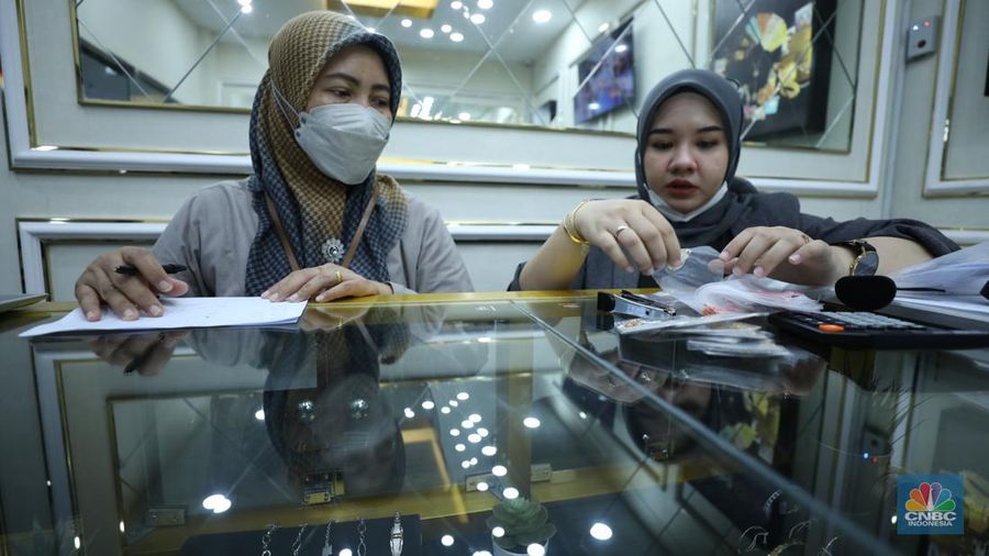 Karyawan menunjukkan emas Antam di gerai Galeri 24 Pegadaian di Jakarta, Senin (5/12/2022). Harga emas batangan di PT Pegadaian bergerak stagnan pada perdagangan hari ini, Senin (5/12/2022). Pegadaian sendiri menjual berbagai jenis emas, yaitu emas Antam, Antam Retro, Antam Batik, dan UBS. Ukurannya pun dijual beragam, mulai dari 0,5 gram hingga 1.000 gram. Pada perdagangan hari ini, harga emas Antam ukuran 1 gram dibanderol Rp 1.033.000. (CNBC Indonesia/Tri Susilo)