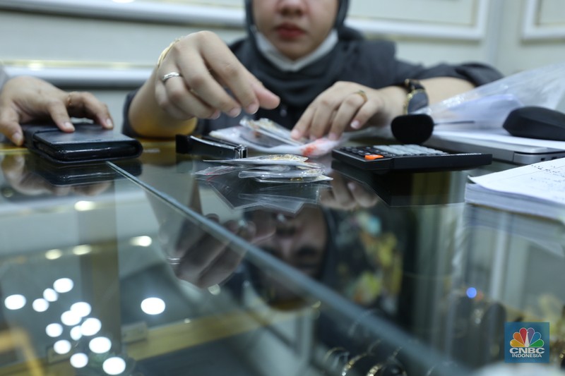 Karyawan menunjukkan emas Antam di gerai Galeri 24 Pegadaian di Jakarta, Senin (5/12/2022). Harga emas batangan di PT Pegadaian bergerak stagnan pada perdagangan hari ini, Senin (5/12/2022). Karyawan menunjukkan emas Antam di gerai Galeri 24 Pegadaian di Jakarta, Senin (5/12/2022). Harga emas batangan di PT Pegadaian bergerak stagnan pada perdagangan hari ini, Senin (5/12/2022). Pegadaian sendiri menjual berbagai jenis emas, yaitu emas Antam, Antam Retro, Antam Batik, dan UBS. Ukurannya pun dijual beragam, mulai dari 0,5 gram hingga 1.000 gram. Pada perdagangan hari ini, harga emas Antam ukuran 1 gram dibanderol Rp 1.033.000. (CNBC Indonesia/Tri Susilo)