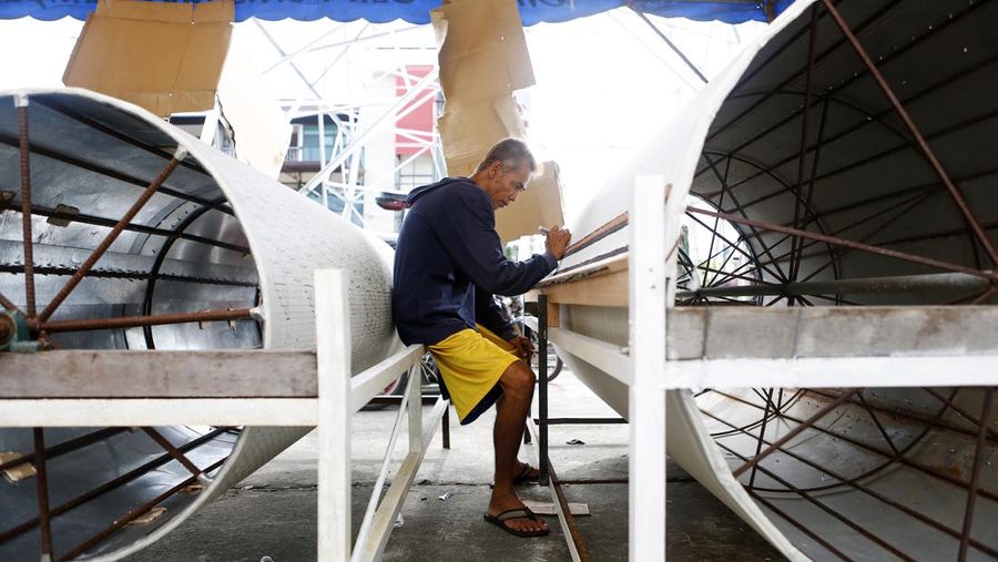 In this Nov. 23, 2017, photo, master lantern maker Teddy Aguilar draws wiring patterns on steel cylinders used to manually manipulate the light in each giant lantern. Skillfully crafted giant lanterns light up the Filipino Christmas spirit in a Philippines province on Dec. 16, ahead of the festive holiday. Ten villages in Pampanga province took part in an annual giant lantern competition, proudly showcasing huge elaborate lanterns for everyone to see. (AP Photo/Iya Forbes)