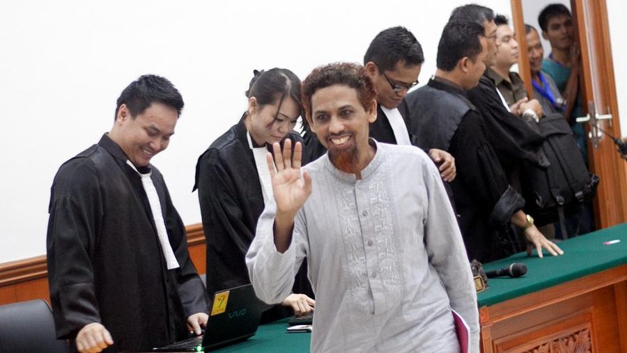 Tersangka teror Indonesia Umar Patek (tengah) melambai kepada wartawan setelah satu hari lagi persidangannya di pengadilan Jakarta pada 4 Juni 2012. Jaksa diharapkan menanggapi pembelaan tersangka pembuat bom Umar Patek atas perannya dalam Bom Bali 2002. (File - Photo credit should read OSCAR SIAGIAN/AFP/GettyImages)