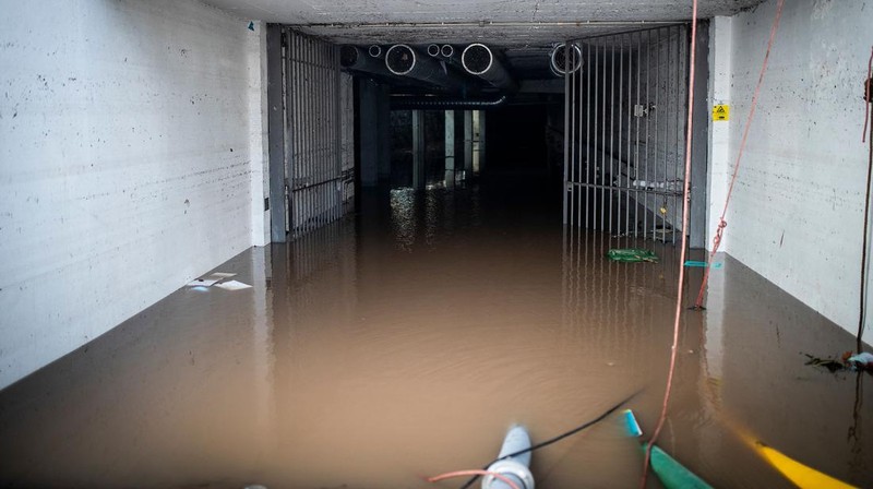 Seorang pria mencoba membuang air berlumpur setelah banjir di Lisbon pada 8 Desember 2022. - Satu orang meninggal tadi malam akibat banjir di wilayah Lisbon, dilanda hujan lebat, kata dinas pertahanan sipil. (CARLOS COSTA/AFP via Getty Images)