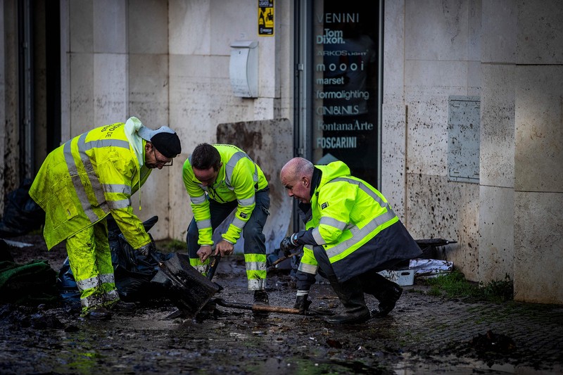 Seorang pria mencoba membuang air berlumpur setelah banjir di Lisbon pada 8 Desember 2022. - Satu orang meninggal tadi malam akibat banjir di wilayah Lisbon, dilanda hujan lebat, kata dinas pertahanan sipil. (CARLOS COSTA/AFP via Getty Images)