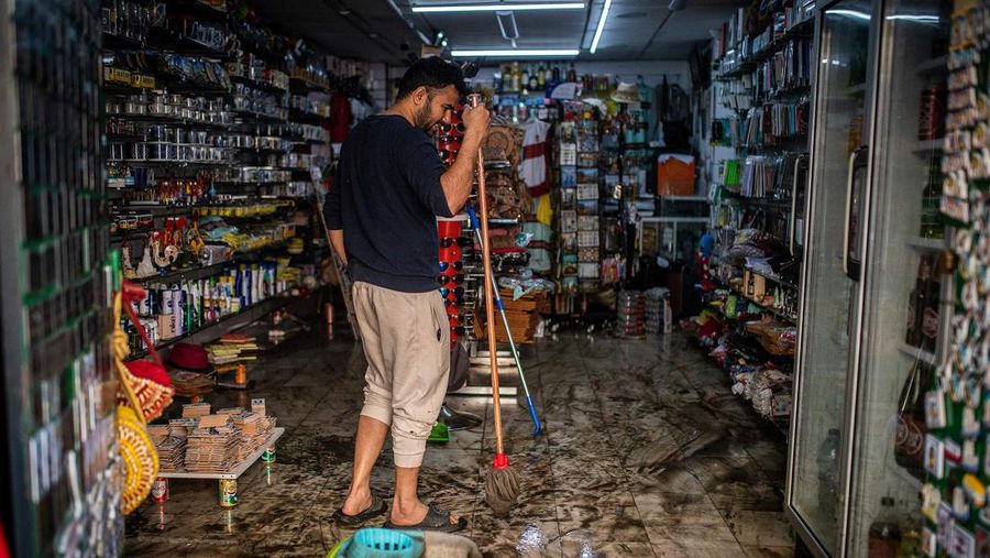 Seorang pria mencoba membuang air berlumpur setelah banjir di Lisbon pada 8 Desember 2022. - Satu orang meninggal tadi malam akibat banjir di wilayah Lisbon, dilanda hujan lebat, kata dinas pertahanan sipil. (CARLOS COSTA/AFP via Getty Images)