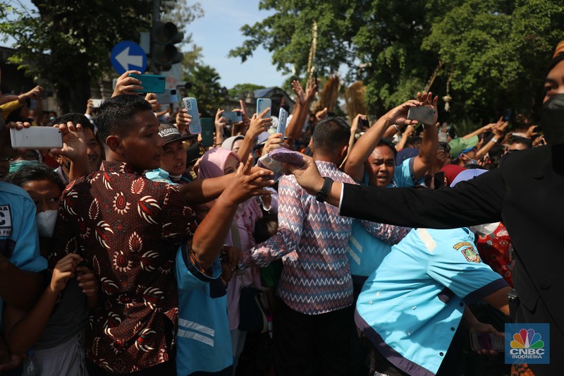 Warga berebut souvenir dari Kaesang Erina di Jalan Slamet Riyadi, Solo, Minggu, 11/12. Souvenir-souvenir tersebut membuat warga Solo yang beruntung menerima merasa sumringah. (CNBC Indonesia/ Muhammad Sabki)
