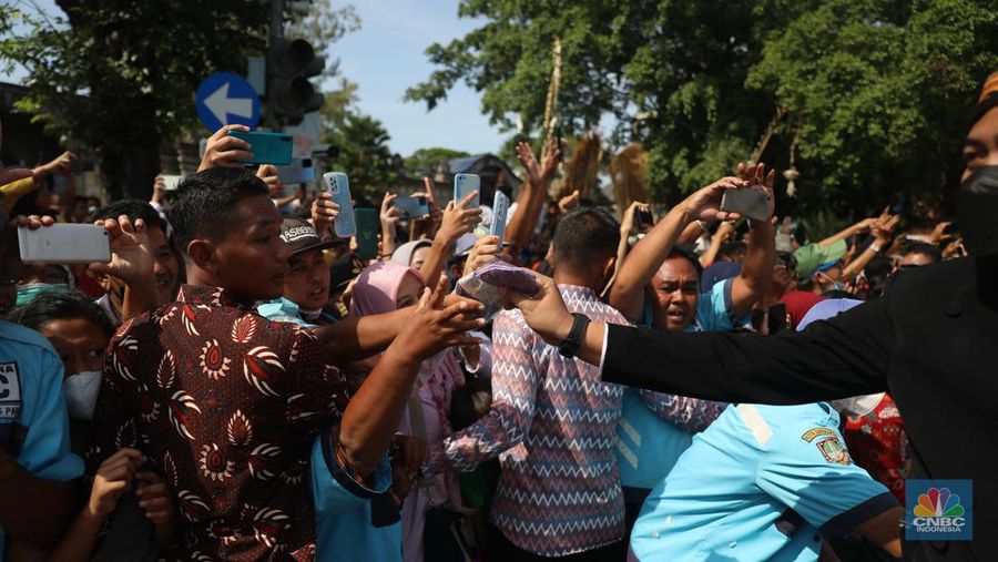 Warga berebut souvenir dari Kaesang Erina di Jalan Slamet Riyadi, Solo, Minggu, 11/12. Souvenir-souvenir tersebut membuat warga Solo yang beruntung menerima merasa sumringah. (CNBC Indonesia/ Muhammad Sabki)