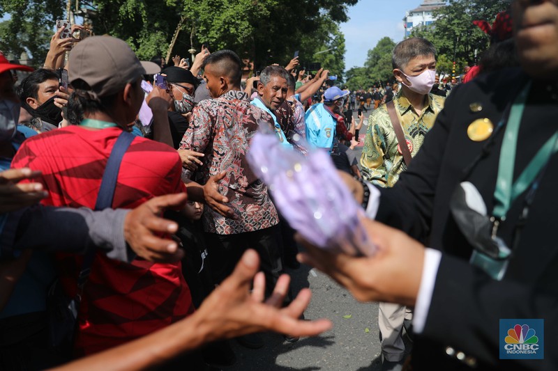 Warga berebut souvenir dari Kaesang Erina di Jalan Slamet Riyadi, Solo, Minggu, 11/12. Souvenir-souvenir tersebut membuat warga Solo yang beruntung menerima merasa sumringah. (CNBC Indonesia/ Muhammad Sabki)