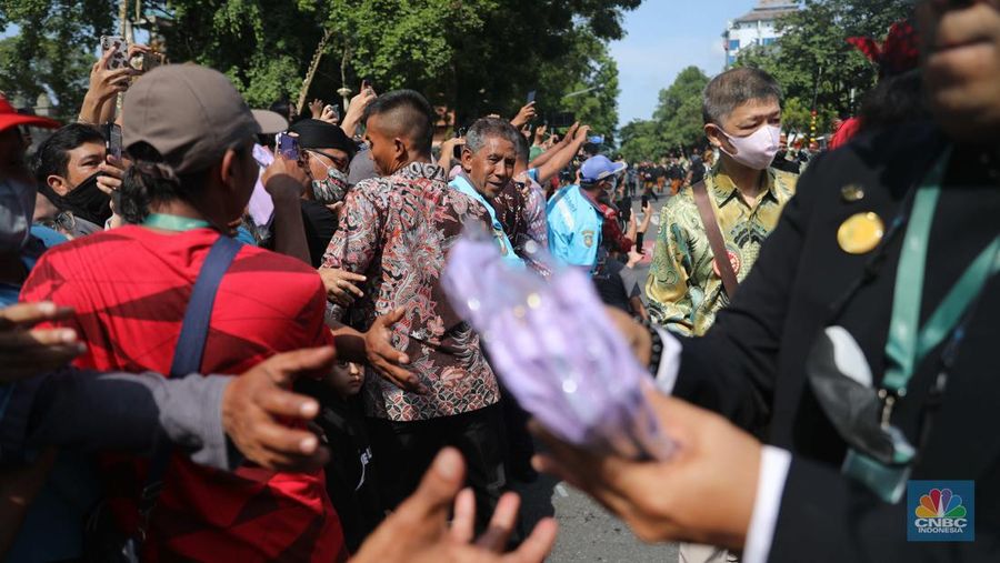 Warga berebut souvenir dari Kaesang Erina di Jalan Slamet Riyadi, Solo, Minggu, 11/12. Souvenir-souvenir tersebut membuat warga Solo yang beruntung menerima merasa sumringah. (CNBC Indonesia/ Muhammad Sabki)