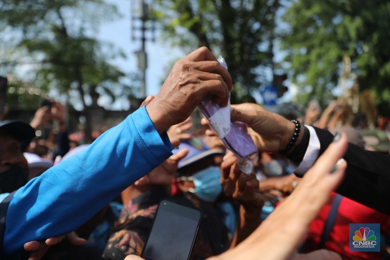 Warga berebut souvenir dari Kaesang Erina di Jalan Slamet Riyadi, Solo, Minggu, 11/12. Souvenir-souvenir tersebut membuat warga Solo yang beruntung menerima merasa sumringah. (CNBC Indonesia/ Muhammad Sabki)