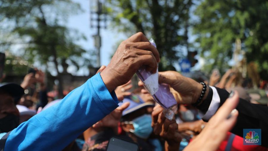 Warga berebut souvenir dari Kaesang Erina di Jalan Slamet Riyadi, Solo, Minggu, 11/12. Souvenir-souvenir tersebut membuat warga Solo yang beruntung menerima merasa sumringah. (CNBC Indonesia/ Muhammad Sabki)