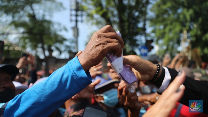 Warga berebut souvenir dari Kaesang Erina di Jalan Slamet Riyadi, Solo, Minggu, 11/12. Souvenir-souvenir tersebut membuat warga Solo yang beruntung menerima merasa sumringah. (CNBC Indonesia/ Muhammad Sabki)