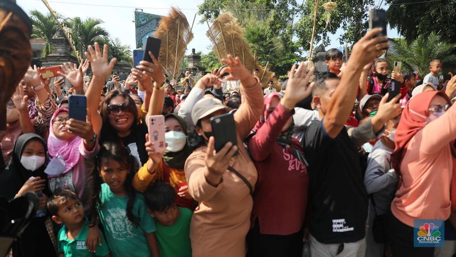 Warga berebut souvenir dari Kaesang Erina di Jalan Slamet Riyadi, Solo, Minggu, 11/12. Souvenir-souvenir tersebut membuat warga Solo yang beruntung menerima merasa sumringah. (CNBC Indonesia/ Muhammad Sabki)