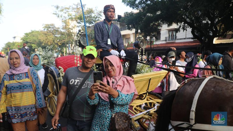 Warga berfoto di depan kereta kencana di Kawasan Car Free Day Slamet Riyadi, Solo, Jawa Tengah, Minggu (11/12). Kaesang Pangarep dan Erina Gudono akan menjalani ngunduh mantu dan tasyakuran hari ini. Acara ngunduh mantu dan tasyakuran Kaesang dan Erina. (CNBC Indonesia/ Muhammad Sabki)