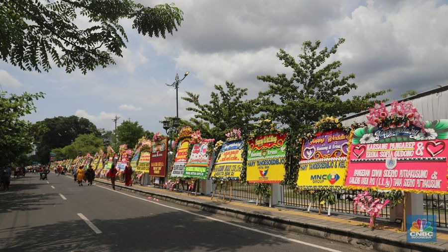 Warga melintas di depan karangan bunga ucapan selamat atas pernikahan Kaesang Pangarep dengan Erina Gudono di depan Pura Mangkunegaran, Solo, Minggu, 11/12. Ratusan karangan bunga ucapan selamat atas pernikahan Kaesang-Erina dikirimkan sejumlah karangan. (CNBC Indonesia/ Muhammad Sabki)