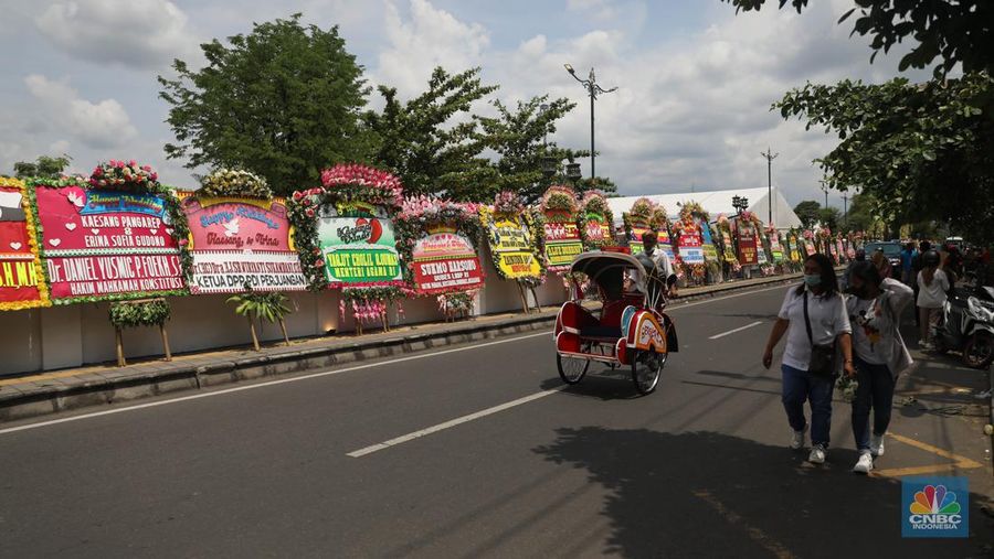 Warga melintas di depan karangan bunga ucapan selamat atas pernikahan Kaesang Pangarep dengan Erina Gudono di depan Pura Mangkunegaran, Solo, Minggu, 11/12. Ratusan karangan bunga ucapan selamat atas pernikahan Kaesang-Erina dikirimkan sejumlah karangan. (CNBC Indonesia/ Muhammad Sabki)