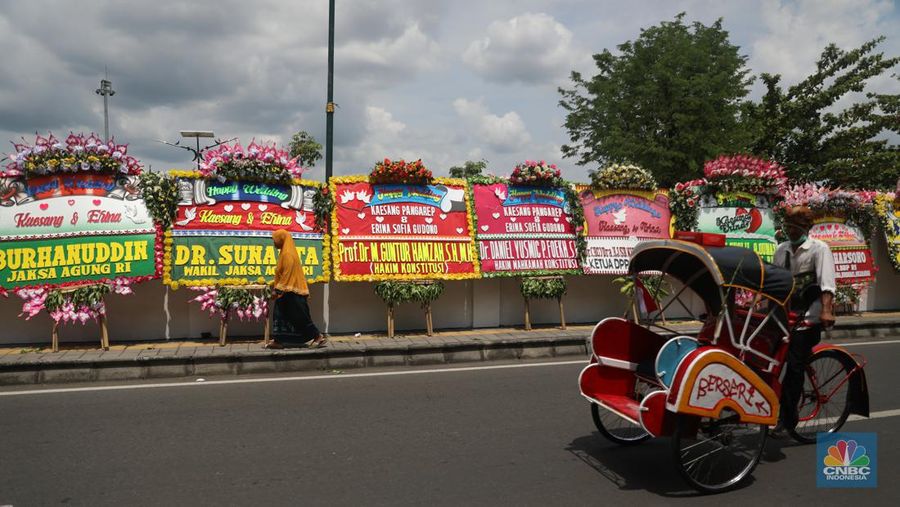 Warga melintas di depan karangan bunga ucapan selamat atas pernikahan Kaesang Pangarep dengan Erina Gudono di depan Pura Mangkunegaran, Solo, Minggu, 11/12. Ratusan karangan bunga ucapan selamat atas pernikahan Kaesang-Erina dikirimkan sejumlah karangan. (CNBC Indonesia/ Muhammad Sabki)