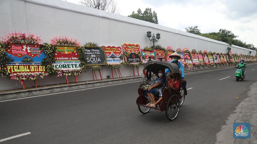 Warga melintas di depan karangan bunga ucapan selamat atas pernikahan Kaesang Pangarep dengan Erina Gudono di depan Pura Mangkunegaran, Solo, Minggu, 11/12. Ratusan karangan bunga ucapan selamat atas pernikahan Kaesang-Erina dikirimkan sejumlah karangan. (CNBC Indonesia/ Muhammad Sabki)