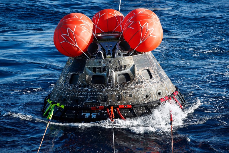 Kapsul Orion NASA berjalan menuju USS Portland (LPD 27) setelah berhasil diamankan oleh tim NASA dan Angkatan Laut AS di lepas pantai Baja California, Meksiko, pada 11 Desember 2022. - Orion diluncurkan 16 November dengan roket Artemis untuk misi 25 hari ke Bulan. Tujuan utama dari misi ini adalah untuk menguji pelindung panas Orion apa cocok untuk manusia berada di dalamnya. (CAROLINE BREHMAN/POOL/AFP via Getty Images)