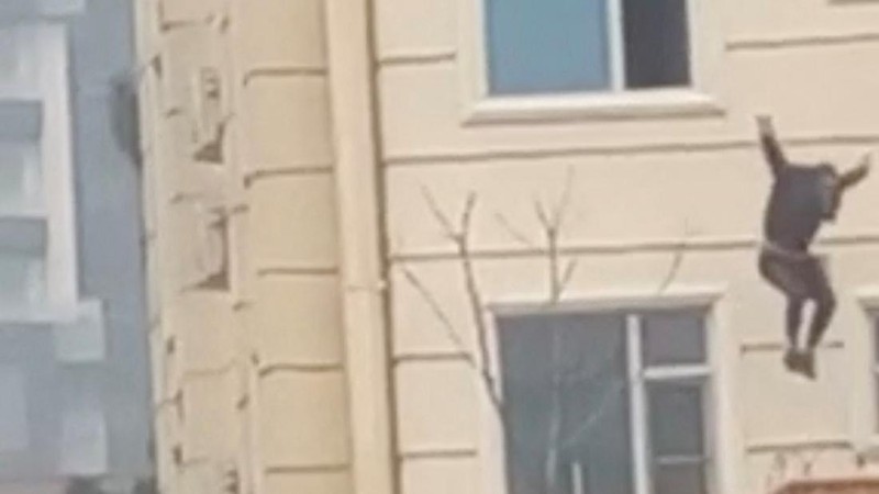 A person prepares to jump from a hotel window in Shahr-e-Naw neighborhood amid sounds of gunfire in Kabul, Afghanistan December 12, 2022 in this still image from video. Aamaj News via REUTERS  THIS IMAGE HAS BEEN SUPPLIED BY A THIRD PARTY. NO RESALES. NO ARCHIVES. MANDATORY CREDIT