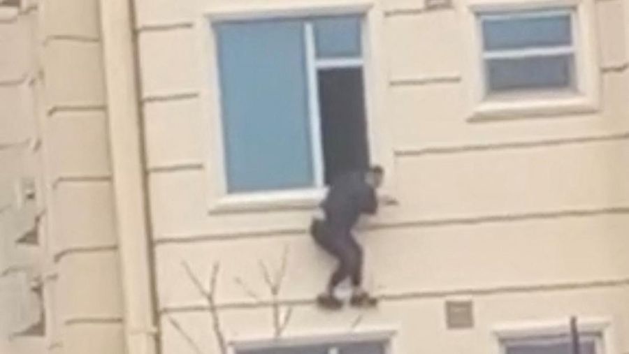A person prepares to jump from a hotel window in Shahr-e-Naw neighborhood amid sounds of gunfire in Kabul, Afghanistan December 12, 2022 in this still image from video. Aamaj News via REUTERS  THIS IMAGE HAS BEEN SUPPLIED BY A THIRD PARTY. NO RESALES. NO ARCHIVES. MANDATORY CREDIT