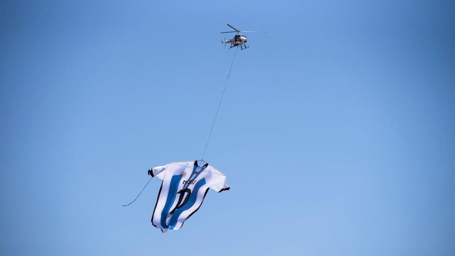 Helikopter membawa t-shirt raksasa penyerang Argentina Lionel Messi di atas Rosario, Argentina, pada 13 Desember 2022, sebelum pertandingan sepak bola semifinal Piala Dunia Qatar 2022 antara Argentina dan Kroasia. (AFP via Getty Images/STR)