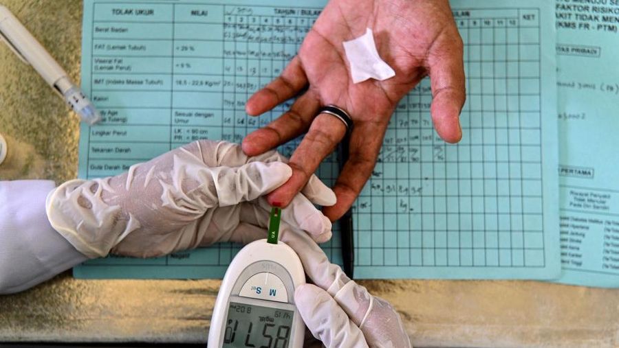 An elderly woman gets her blood tested during a drive to provide medical check-ups for hypertension, cholesterol and diabetes at an integrated services post in Banda Aceh on December 15, 2021. (Photo by CHAIDEER MAHYUDDIN / AFP) (Photo by CHAIDEER MAHYUDDIN/AFP via Getty Images)