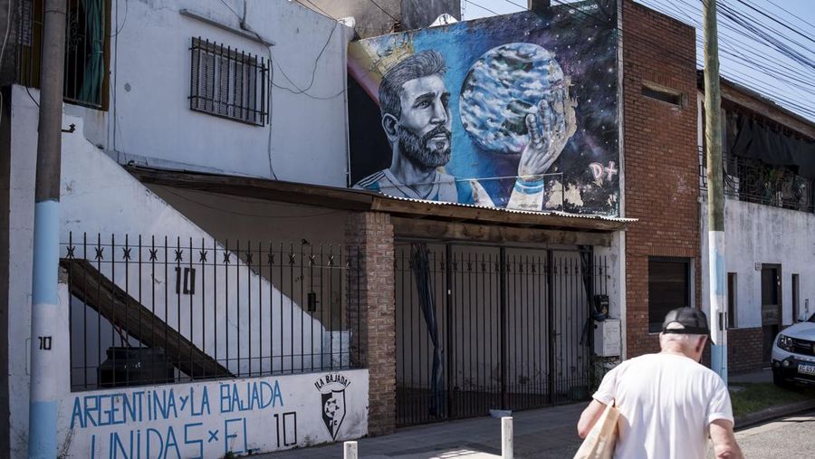 Seorang pria berjalan melewati mural yang menggambarkan bintang sepak bola Argentina Lionel Messi. (AFP via Getty Images/MARCELO MANERA)