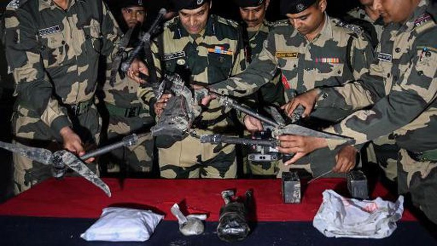 Indian Border Security Force (BSF) personnel display a drone and packets of drugs during a media briefing after it was confiscated from near the border outpost of Roranwala about 40kms from Amritsar on December 5, 2022. (Photo by Narinder NANU / AFP)