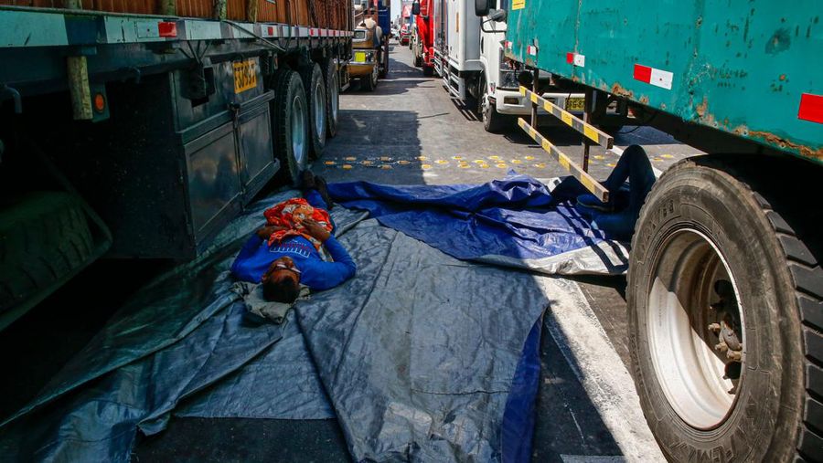 Seorang pengemudi truk beristirahat di tanah saat pengunjuk rasa memblokir Jalan Raya Pan-Amerika yang menuntut pemilihan dini dan pembebasan mantan Presiden Peru Pedro Castillo di Ica, Peru selatan, pada 13 Desember 2022. (AFP via Getty Images/STR)