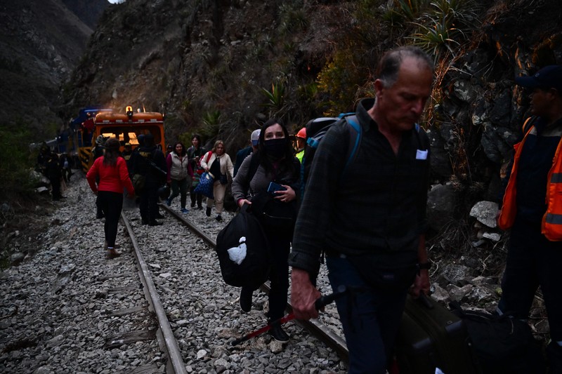 Turis yang terdampar usai mengunjungi benteng Inca di Machu Picchu treck dievakuasi dengan kereta api ke Ollantaytambo, Peru, Sabtu (17/12/2022). Ratusan turis terlantar di Kota Machu Picchu karena akses kereta dihentikan usai Peru mendeklarasikan status darurat menyusul pemakzulan dan penahanan mantan presiden Pedro Castillo pada tengah pekan ini. Kedaruratan ini dipicu krisis politik dan kerusuhan berdarah yang hingga kini sudah menewaskan setidaknya 20 orang dan 340 lainnya luka-luka. (Photo by MARTIN BERNETTI/AFP via Getty Images)