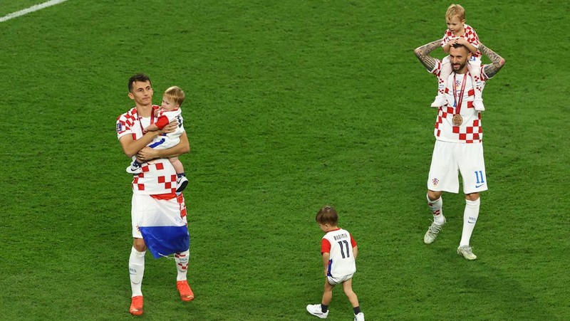 Pemain Kroasia Ante Budimir dan Marcelo Brozovic mengenakan medali saat mereka merayakannya bersama anak-anak di lapangan usai pertandingan sepak bola perebutan tempat ketiga Piala Dunia antara Kroasia dan Maroko di Stadion Internasional Khalifa di Doha, Qatar, Sabtu (17/12/2022). Kroasia berhasil mengalahkan Maroko 2-1 pada perebutan posisi ketiga Piala Dunia 2022. Hasil itu menobatkan Kroasia sebagai juara ketiga pada Piala Dunia edisi kali ini. (REUTERS/Bernadett Szabo)