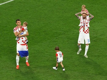 Pemain Kroasia Ante Budimir dan Marcelo Brozovic mengenakan medali saat mereka merayakannya bersama anak-anak di lapangan usai pertandingan sepak bola perebutan tempat ketiga Piala Dunia antara Kroasia dan Maroko di Stadion Internasional Khalifa di D