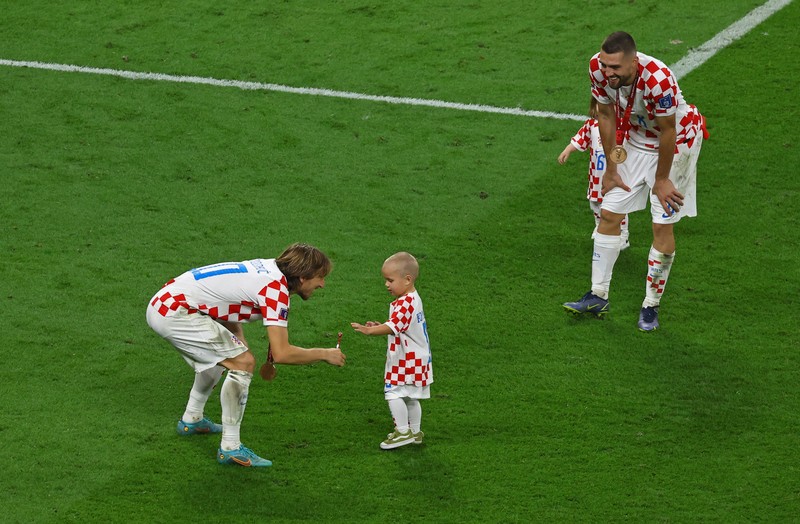 Pemain Kroasia Ante Budimir dan Marcelo Brozovic mengenakan medali saat mereka merayakannya bersama anak-anak di lapangan usai pertandingan sepak bola perebutan tempat ketiga Piala Dunia antara Kroasia dan Maroko Pemain Kroasia Ante Budimir dan Marcelo Brozovic mengenakan medali saat mereka merayakannya bersama anak-anak di lapangan usai pertandingan sepak bola perebutan tempat ketiga Piala Dunia antara Kroasia dan Maroko di Stadion Internasional Khalifa di Doha, Qatar, Sabtu (17/12/2022). Kroasia berhasil mengalahkan Maroko 2-1 pada perebutan posisi ketiga Piala Dunia 2022. Hasil itu menobatkan Kroasia sebagai juara ketiga pada Piala Dunia edisi kali ini. (REUTERS/Bernadett Szabo)