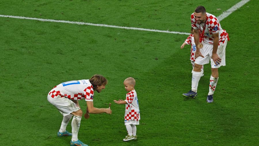 Pemain Kroasia Ante Budimir dan Marcelo Brozovic mengenakan medali saat mereka merayakannya bersama anak-anak di lapangan usai pertandingan sepak bola perebutan tempat ketiga Piala Dunia antara Kroasia dan Maroko di Stadion Internasional Khalifa di Doha, Qatar, Sabtu (17/12/2022). Kroasia berhasil mengalahkan Maroko 2-1 pada perebutan posisi ketiga Piala Dunia 2022. Hasil itu menobatkan Kroasia sebagai juara ketiga pada Piala Dunia edisi kali ini. (REUTERS/Bernadett Szabo)