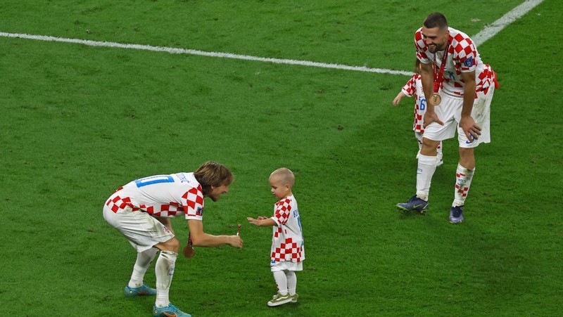 Pemain Kroasia Ante Budimir dan Marcelo Brozovic mengenakan medali saat mereka merayakannya bersama anak-anak di lapangan usai pertandingan sepak bola perebutan tempat ketiga Piala Dunia antara Kroasia dan Maroko di Stadion Internasional Khalifa di Doha, Qatar, Sabtu (17/12/2022). Kroasia berhasil mengalahkan Maroko 2-1 pada perebutan posisi ketiga Piala Dunia 2022. Hasil itu menobatkan Kroasia sebagai juara ketiga pada Piala Dunia edisi kali ini. (REUTERS/Bernadett Szabo)
