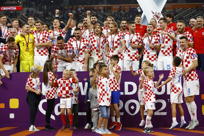 Pemain Kroasia Ante Budimir dan Marcelo Brozovic mengenakan medali saat mereka merayakannya bersama anak-anak di lapangan usai pertandingan sepak bola perebutan tempat ketiga Piala Dunia antara Kroasia dan Maroko Pemain Kroasia Ante Budimir dan Marcelo Brozovic mengenakan medali saat mereka merayakannya bersama anak-anak di lapangan usai pertandingan sepak bola perebutan tempat ketiga Piala Dunia antara Kroasia dan Maroko di Stadion Internasional Khalifa di Doha, Qatar, Sabtu (17/12/2022). Kroasia berhasil mengalahkan Maroko 2-1 pada perebutan posisi ketiga Piala Dunia 2022. Hasil itu menobatkan Kroasia sebagai juara ketiga pada Piala Dunia edisi kali ini. (REUTERS/Bernadett Szabo)