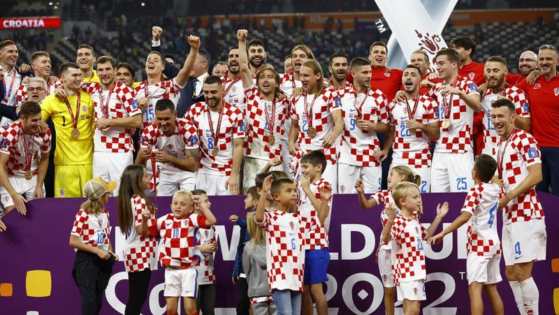 Pemain Kroasia Ante Budimir dan Marcelo Brozovic mengenakan medali saat mereka merayakannya bersama anak-anak di lapangan usai pertandingan sepak bola perebutan tempat ketiga Piala Dunia antara Kroasia dan Maroko di Stadion Internasional Khalifa di Doha, Qatar, Sabtu (17/12/2022). Kroasia berhasil mengalahkan Maroko 2-1 pada perebutan posisi ketiga Piala Dunia 2022. Hasil itu menobatkan Kroasia sebagai juara ketiga pada Piala Dunia edisi kali ini. (REUTERS/Bernadett Szabo)