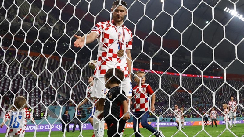 Pemain Kroasia Ante Budimir dan Marcelo Brozovic mengenakan medali saat mereka merayakannya bersama anak-anak di lapangan usai pertandingan sepak bola perebutan tempat ketiga Piala Dunia antara Kroasia dan Maroko di Stadion Internasional Khalifa di Doha, Qatar, Sabtu (17/12/2022). Kroasia berhasil mengalahkan Maroko 2-1 pada perebutan posisi ketiga Piala Dunia 2022. Hasil itu menobatkan Kroasia sebagai juara ketiga pada Piala Dunia edisi kali ini. (REUTERS/Bernadett Szabo)